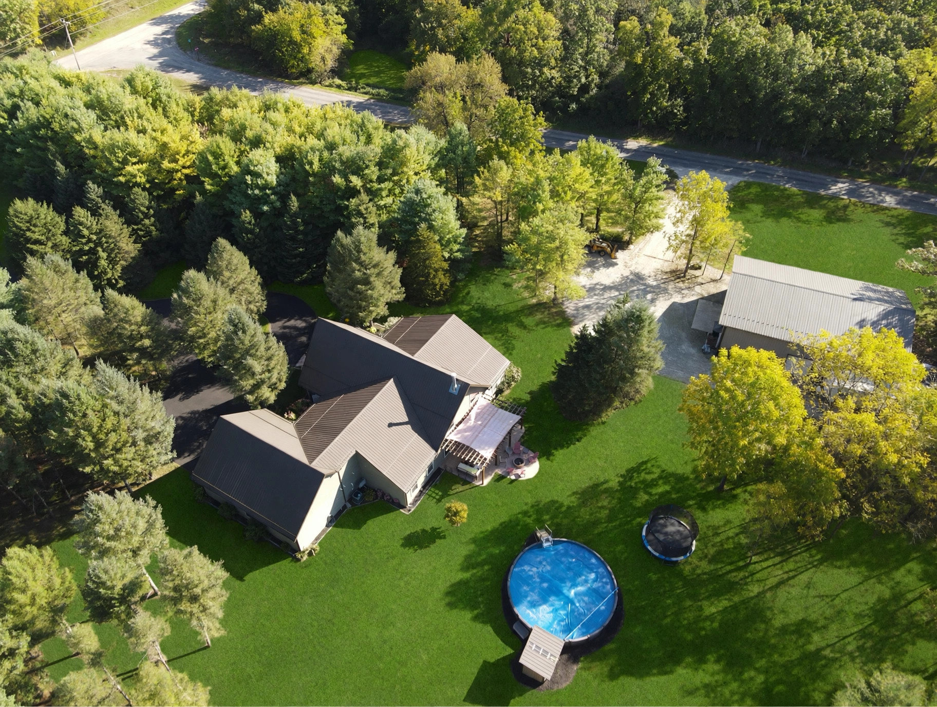 Angled aerial view of house, pool and barn in the trees