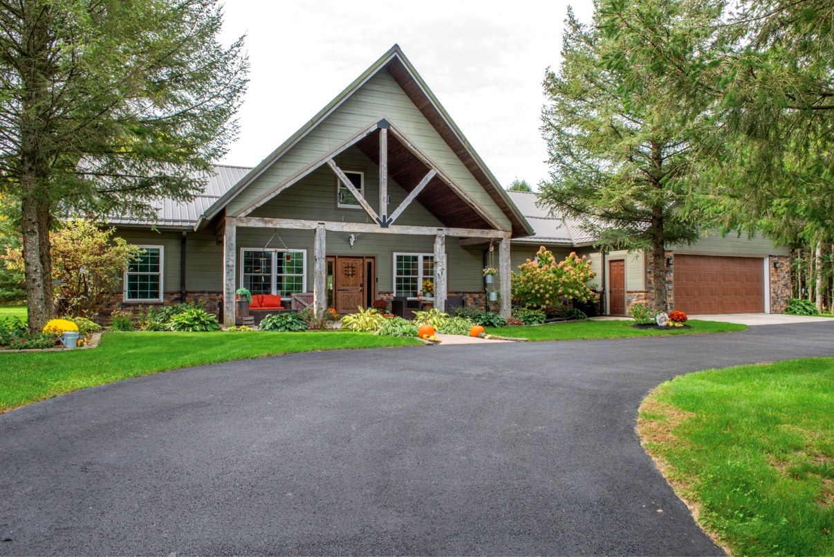 Front exterior of home with covered porch surrounded by pine trees