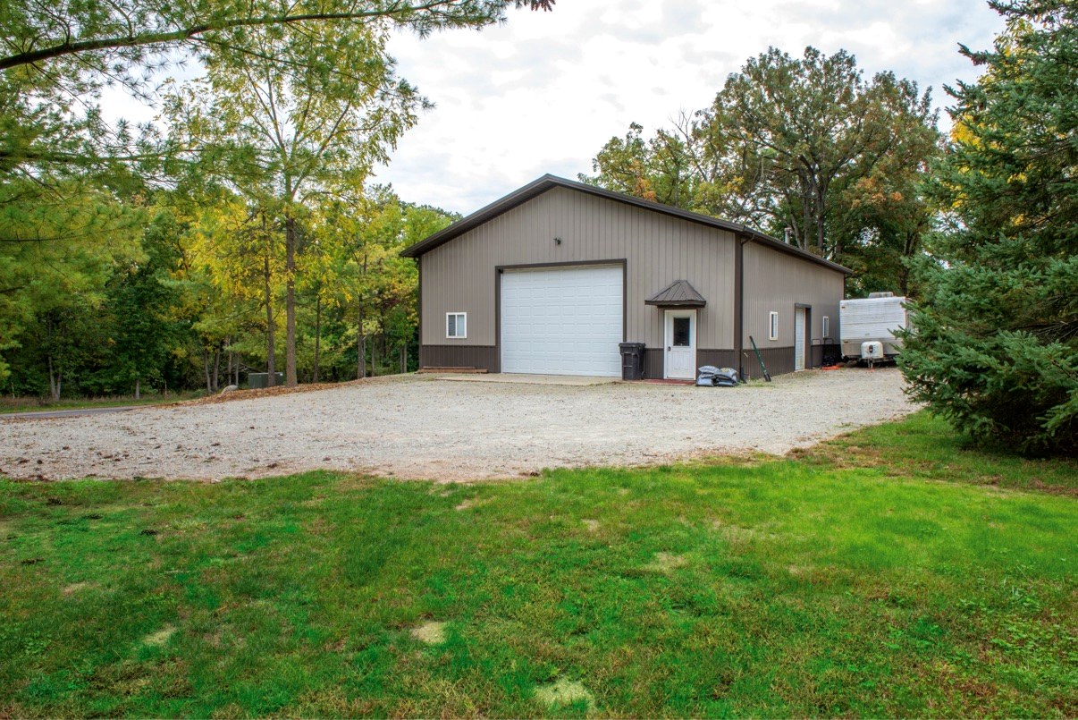40 by 56 pole barn with large overhead door on gravel drive