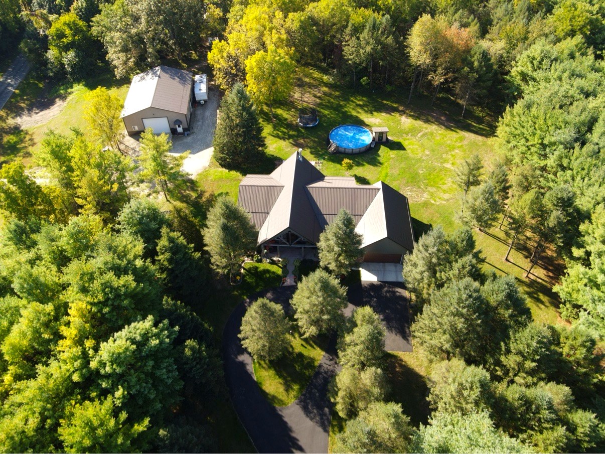 Aerial view showing house, pool, pole barn and tree cover